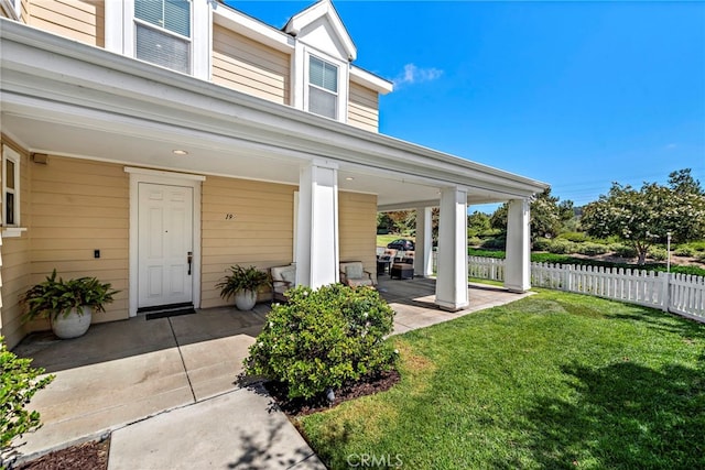 doorway to property with a lawn, a porch, and fence