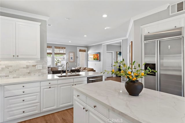 kitchen with visible vents, backsplash, open floor plan, appliances with stainless steel finishes, and a sink