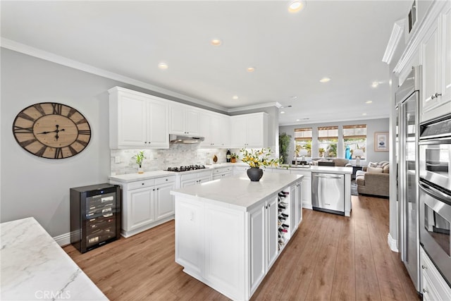 kitchen with backsplash, crown molding, under cabinet range hood, beverage cooler, and appliances with stainless steel finishes