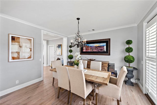 dining area with baseboards, visible vents, an inviting chandelier, light wood-style floors, and crown molding