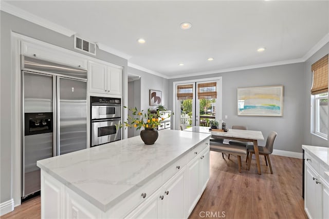 kitchen with visible vents, plenty of natural light, appliances with stainless steel finishes, and ornamental molding