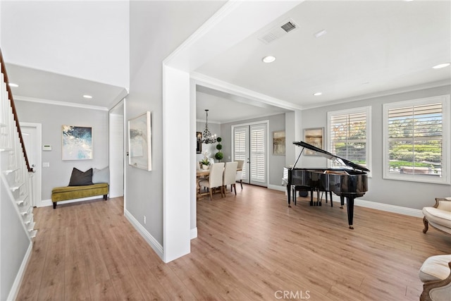 foyer with light wood-type flooring, baseboards, visible vents, and ornamental molding