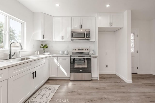 kitchen featuring a wealth of natural light, white cabinets, appliances with stainless steel finishes, and a sink