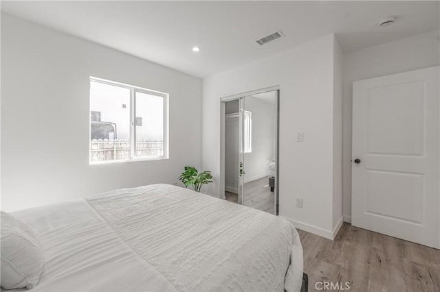 bedroom featuring visible vents, baseboards, light wood-type flooring, recessed lighting, and a closet