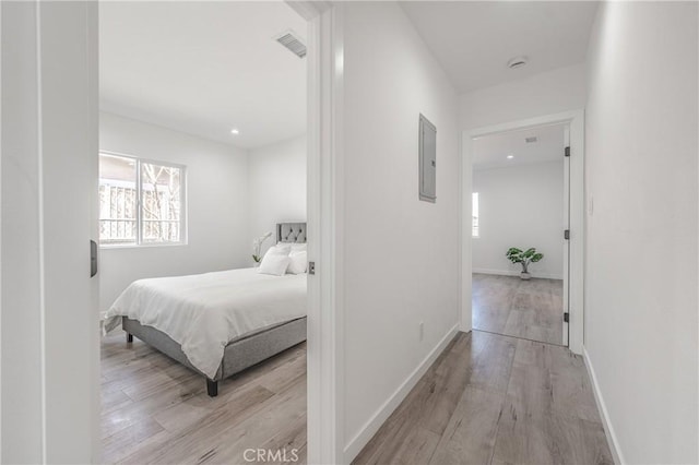 bedroom with electric panel, baseboards, visible vents, and light wood-type flooring