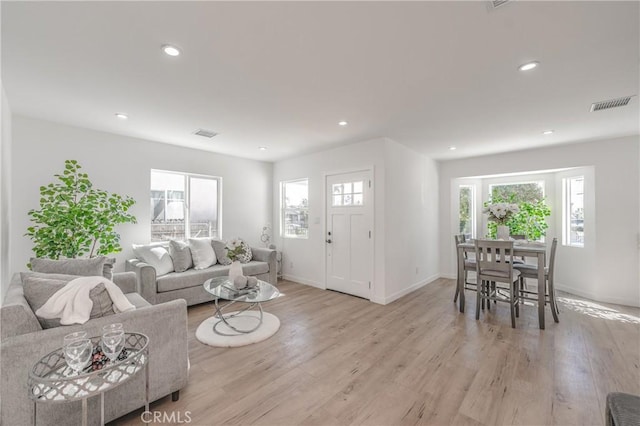 living room with recessed lighting, visible vents, and light wood finished floors