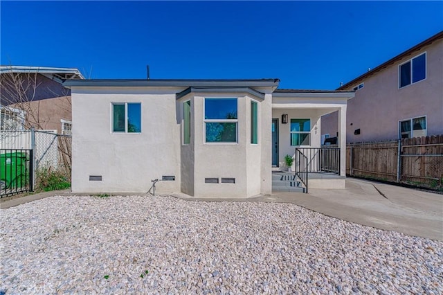 rear view of property with stucco siding, fence, and crawl space