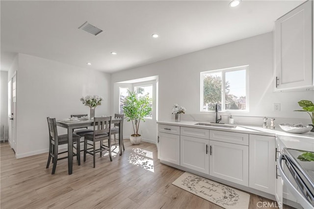 kitchen featuring light wood finished floors, visible vents, recessed lighting, stainless steel range with electric cooktop, and a sink