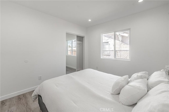 bedroom with a closet, recessed lighting, baseboards, and wood finished floors