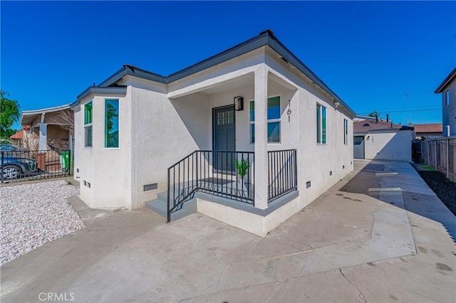 view of side of home with crawl space, stucco siding, and fence