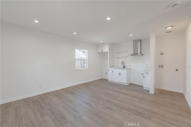 unfurnished living room featuring a sink, baseboards, recessed lighting, and light wood finished floors