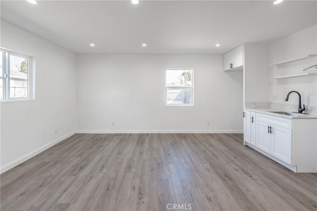 interior space with a sink, open shelves, a healthy amount of sunlight, and white cabinets