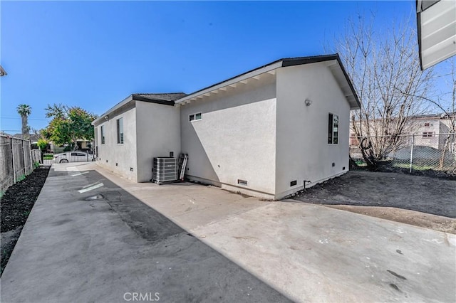 view of home's exterior with crawl space, stucco siding, a patio, and fence