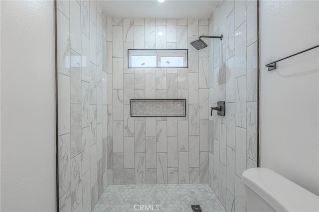 bathroom featuring a tile shower and toilet