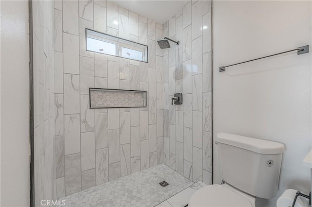 bathroom featuring a tile shower and toilet