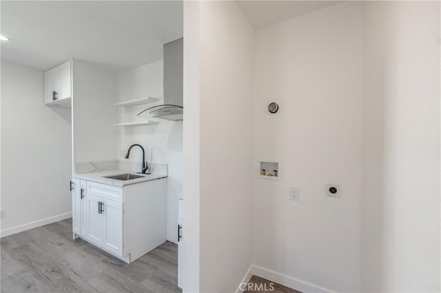 washroom with hookup for an electric dryer, laundry area, a sink, washer hookup, and light wood-type flooring