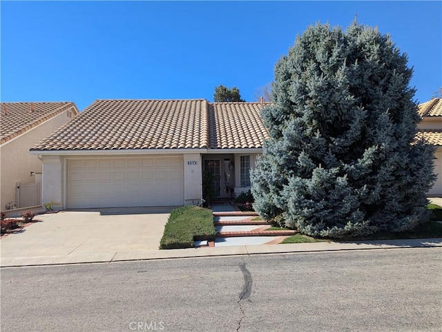 view of front of property with concrete driveway, a tiled roof, a garage, and stucco siding