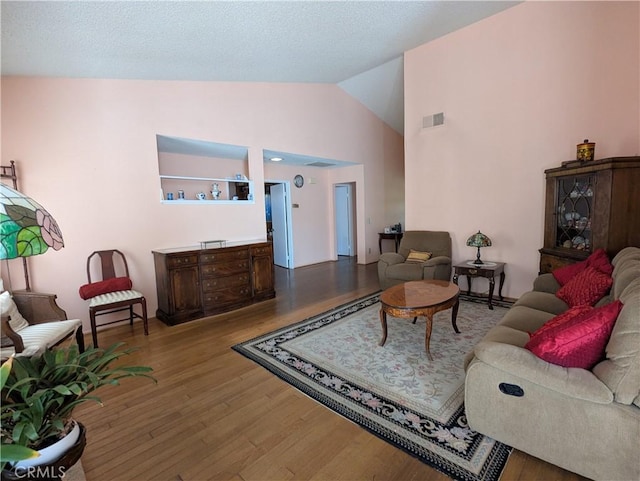 living room featuring visible vents, high vaulted ceiling, and wood finished floors