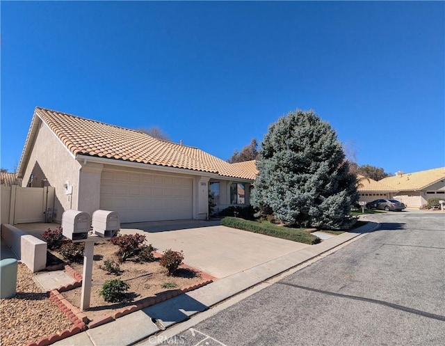 view of front of house with stucco siding, a tile roof, fence, concrete driveway, and an attached garage