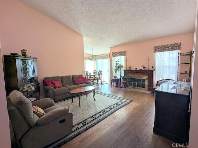 living room featuring a glass covered fireplace, a textured ceiling, and wood finished floors