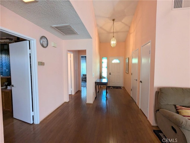 entryway featuring vaulted ceiling, visible vents, and dark wood-style flooring