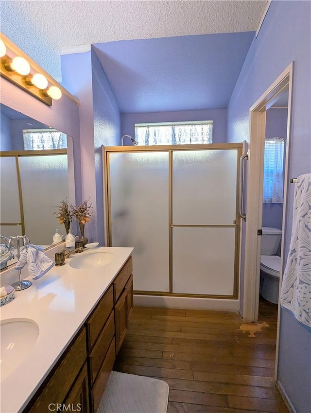 bathroom with double vanity, a stall shower, hardwood / wood-style floors, and a sink