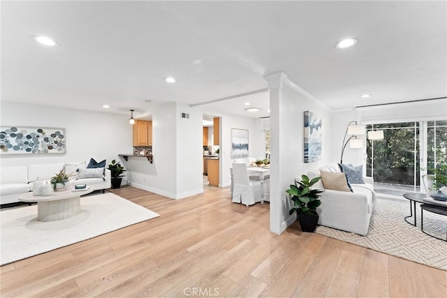 living room with visible vents, ornamental molding, recessed lighting, light wood-style floors, and baseboards