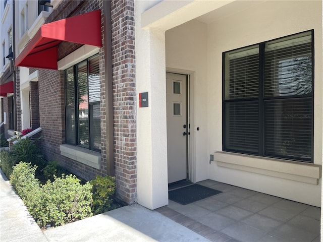 doorway to property featuring brick siding and stucco siding