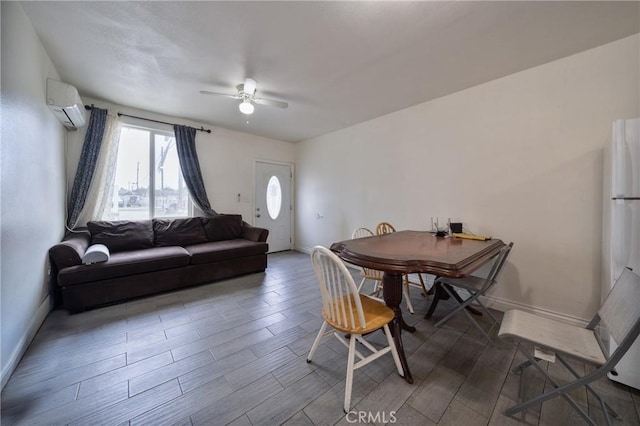 dining area featuring a wall mounted air conditioner, baseboards, wood finished floors, and ceiling fan