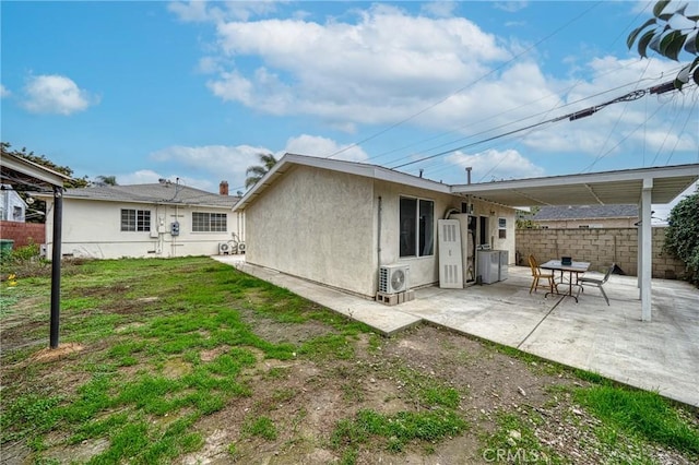 rear view of property featuring fence, stucco siding, ac unit, a patio area, and a lawn