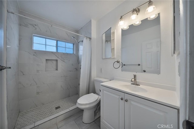 bathroom featuring tiled shower, toilet, and vanity