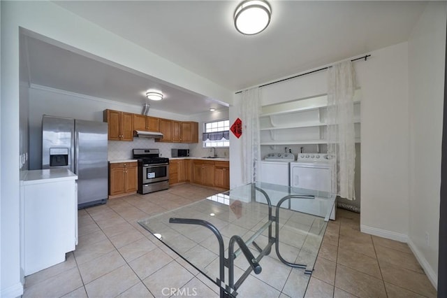 kitchen with brown cabinets, separate washer and dryer, appliances with stainless steel finishes, light countertops, and light tile patterned floors