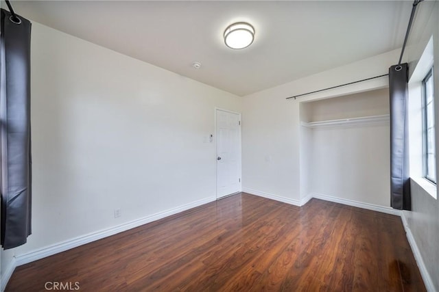 unfurnished bedroom with a closet, baseboards, and wood finished floors