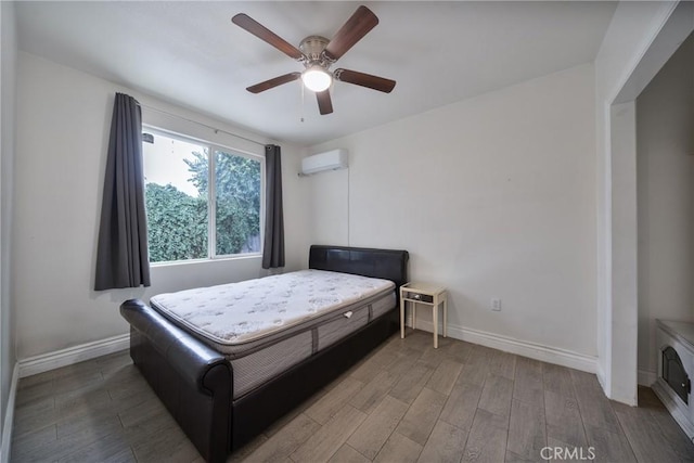 bedroom with baseboards, wood finished floors, a ceiling fan, and a wall mounted AC