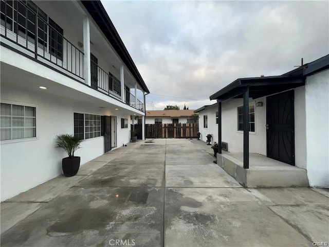 view of side of property featuring stucco siding, a patio, and fence