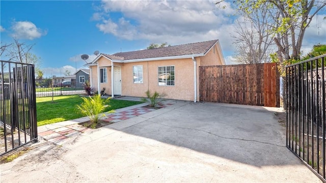 view of front of property with a gate, stucco siding, a front yard, and fence