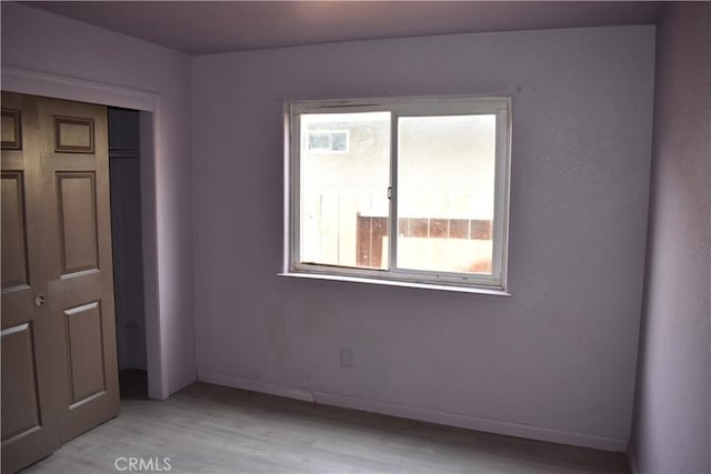 unfurnished bedroom featuring a closet, baseboards, and light wood-style floors