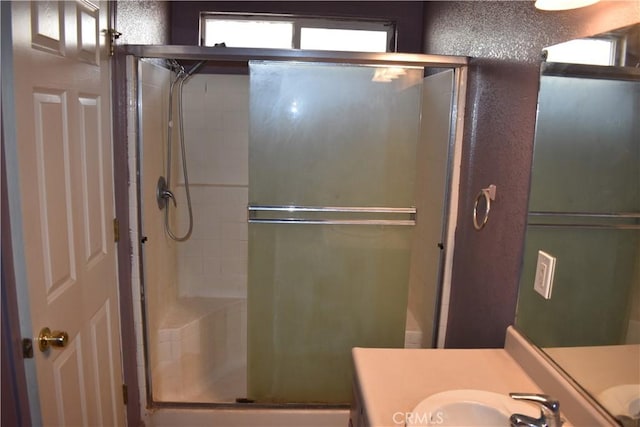 bathroom with a stall shower, vanity, and a textured wall