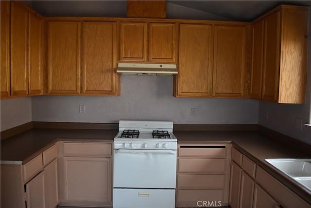 kitchen featuring white gas range, under cabinet range hood, and brown cabinets