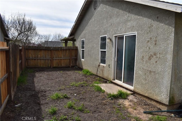 view of property exterior with stucco siding and fence