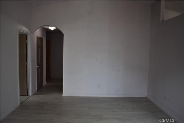 spare room featuring arched walkways and light wood finished floors