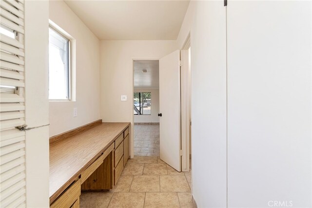 hallway featuring light tile patterned flooring and a healthy amount of sunlight