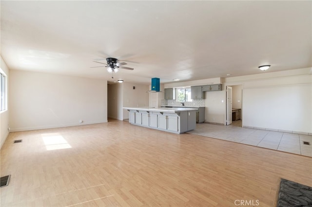 unfurnished living room featuring light wood finished floors, visible vents, and ceiling fan