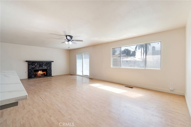 unfurnished living room featuring visible vents, a fireplace, baseboards, and light wood-style floors