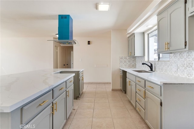 kitchen with gray cabinetry, island exhaust hood, a sink, light tile patterned floors, and decorative backsplash