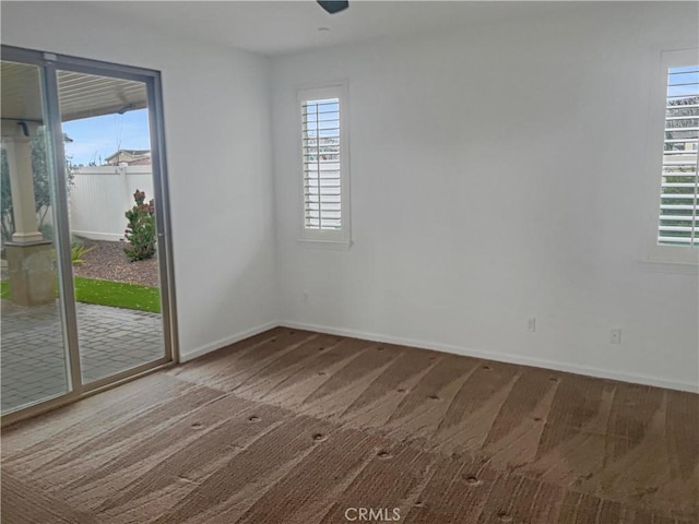 empty room with carpet flooring, baseboards, and a wealth of natural light