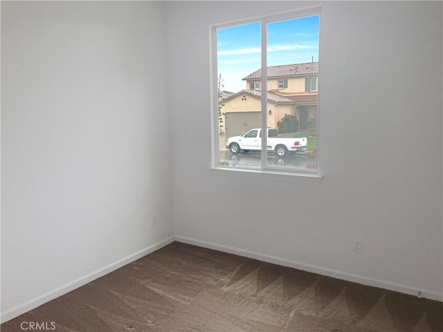 carpeted empty room featuring baseboards