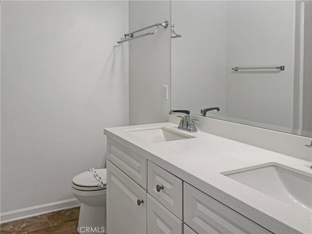 full bath with double vanity, toilet, baseboards, and a sink