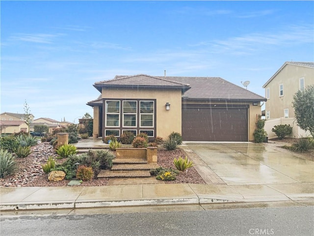 view of front of property with stucco siding, an attached garage, driveway, and fence