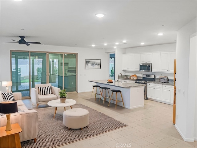 living area with a wealth of natural light, recessed lighting, a ceiling fan, and baseboards